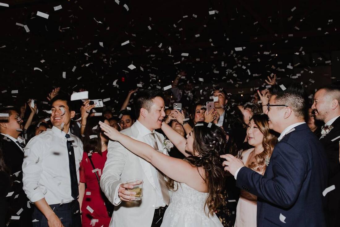 Guests celebrating under falling confetti at a reception